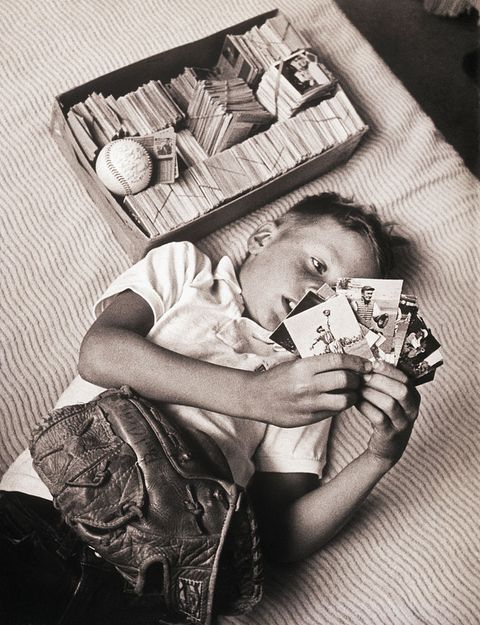 Boy Lying on Bed Studying Baseball Cards