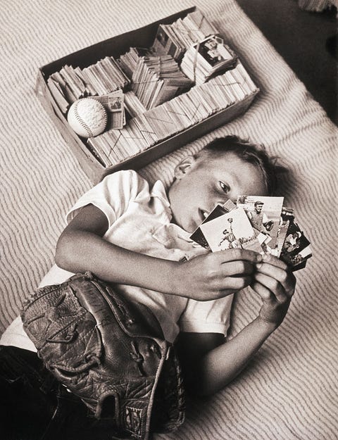 Boy Lying on Bed Studying Baseball Cards boy lying on bed studying baseball cards