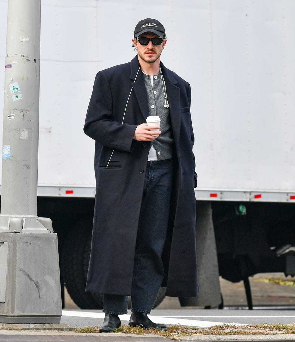 person standing on a street corner holding a coffee cup