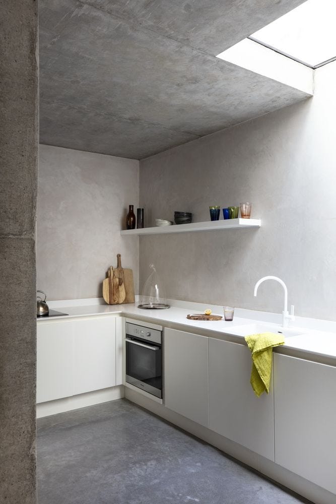 White corner kitchen with clay plaster walls, and shelf