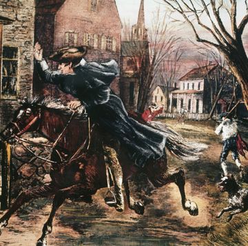 a man riding a galloping horse waves to two people staring out from a doorway, other buildings and people are in the background