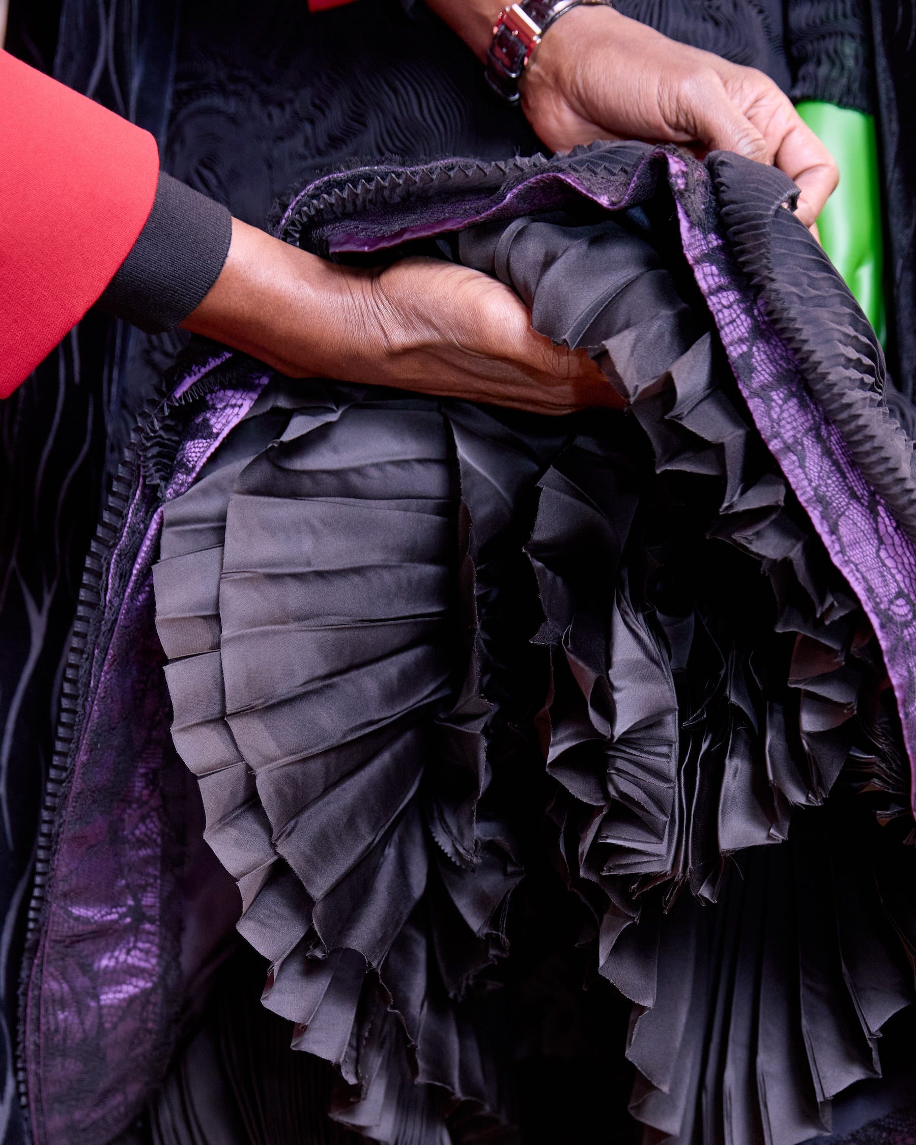 closeup of hands holding intricate fabric with pleats and ruffles