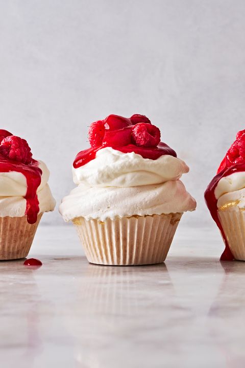 pavlova cupcakes topped with whipped cream and raspberry sauce
