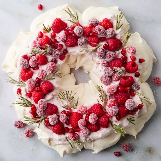 Pavlova Wreath pavlova in a circle topped with sugared cranberries, rosemary, and raspberries