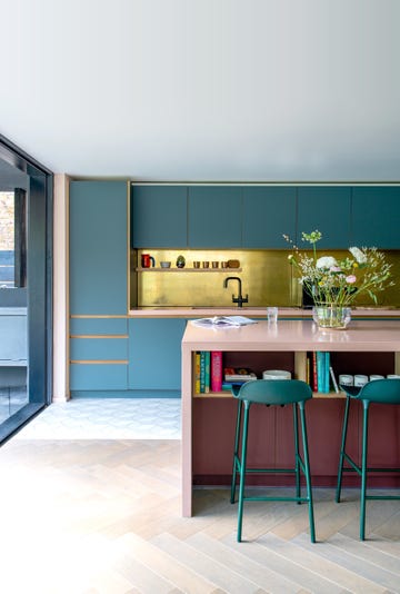 pink concrete island, green cabinets, brass splash back, bar stools