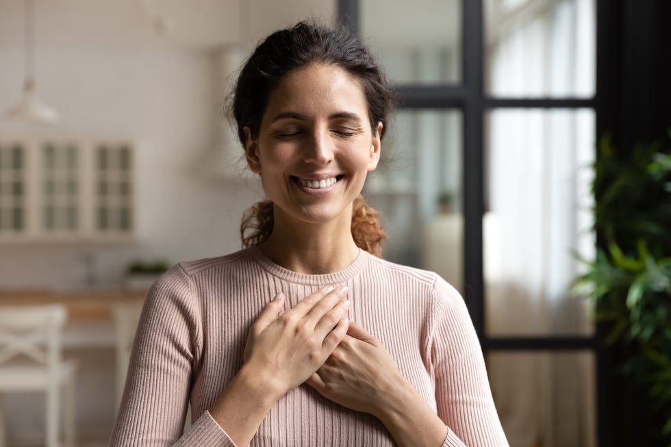 peaceful hispanic female with closed eyes keep hands to heart