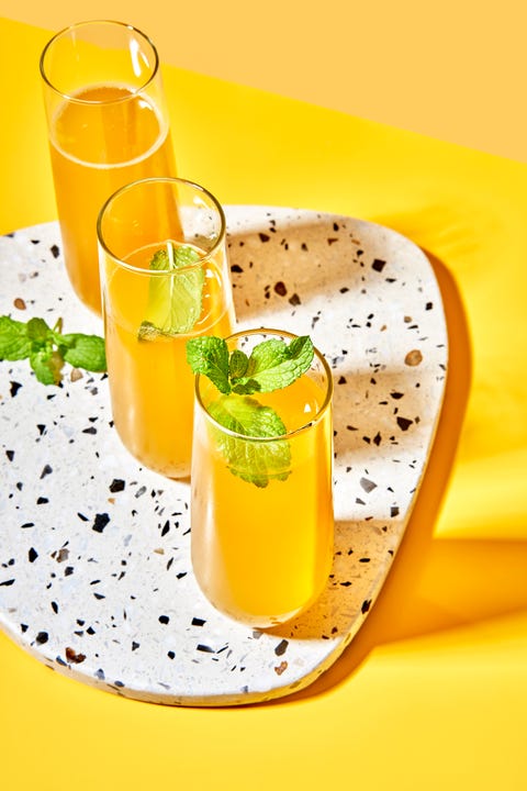 yellow peach bellinis on a white marble speckled tray on a yellow background