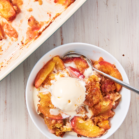 easy peach cobbler in a bowl topped with vanilla ice cream