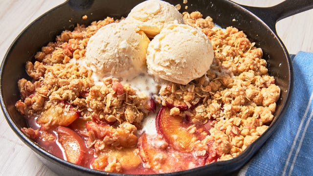 peach crisp in a skillet topped with vanilla ice cream