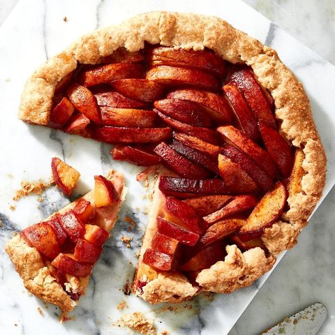 peach galette with a slice out on a marble background