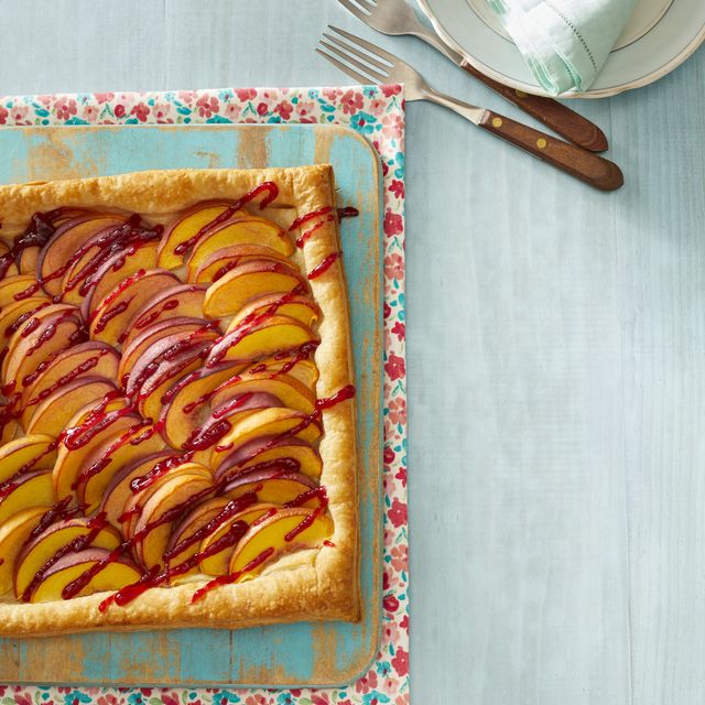 peach melba tart on blue wood surface forks on top right