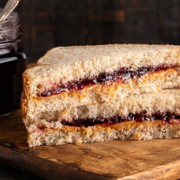 a peanut butter and grape jelly sandwich on a wooden cutting board