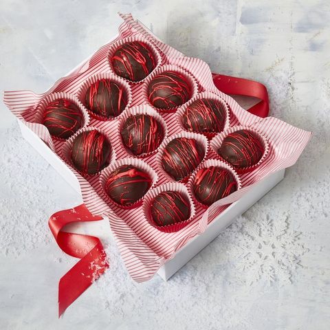 peanut butter balls with melted red candy drizzled on top in a box