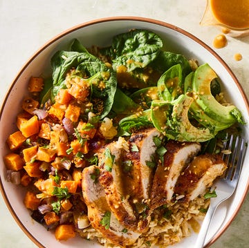 sliced chicken in a grain bowl with sweet potatoes, avocados, spinach and a peanut dressing