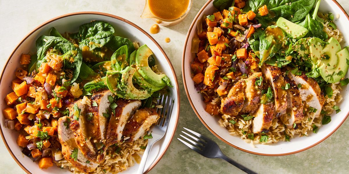 sliced chicken in a grain bowl with sweet potatoes, avocados, spinach and a peanut dressing