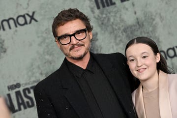 pedro pascal, wearing a black suit and glasses, and bella ramsey, wearing a peach dress suit, smiling for publicity photos