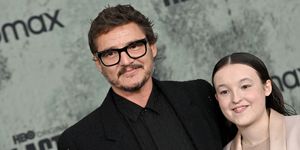 pedro pascal, wearing a black suit and glasses, and bella ramsey, wearing a peach dress suit, smiling for publicity photos