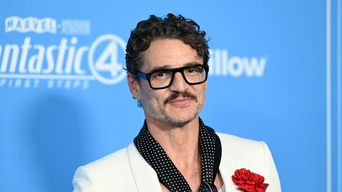 pedro pascal poses wearing white suit jacket and polka dot scarf