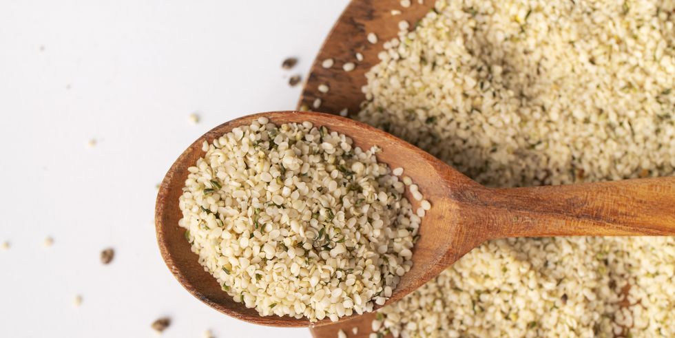 peeled hemp seeds in wooden spoon on light background, top view. superfood, healthy tasty organic hemp seeds, source of omega 3 fatty acids, protein. supplement to healthy diet