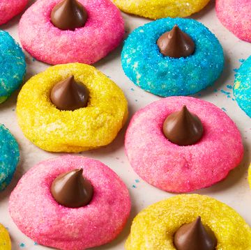 blue pink and yellow dyed cookies with sugar and topped with a hershey kiss