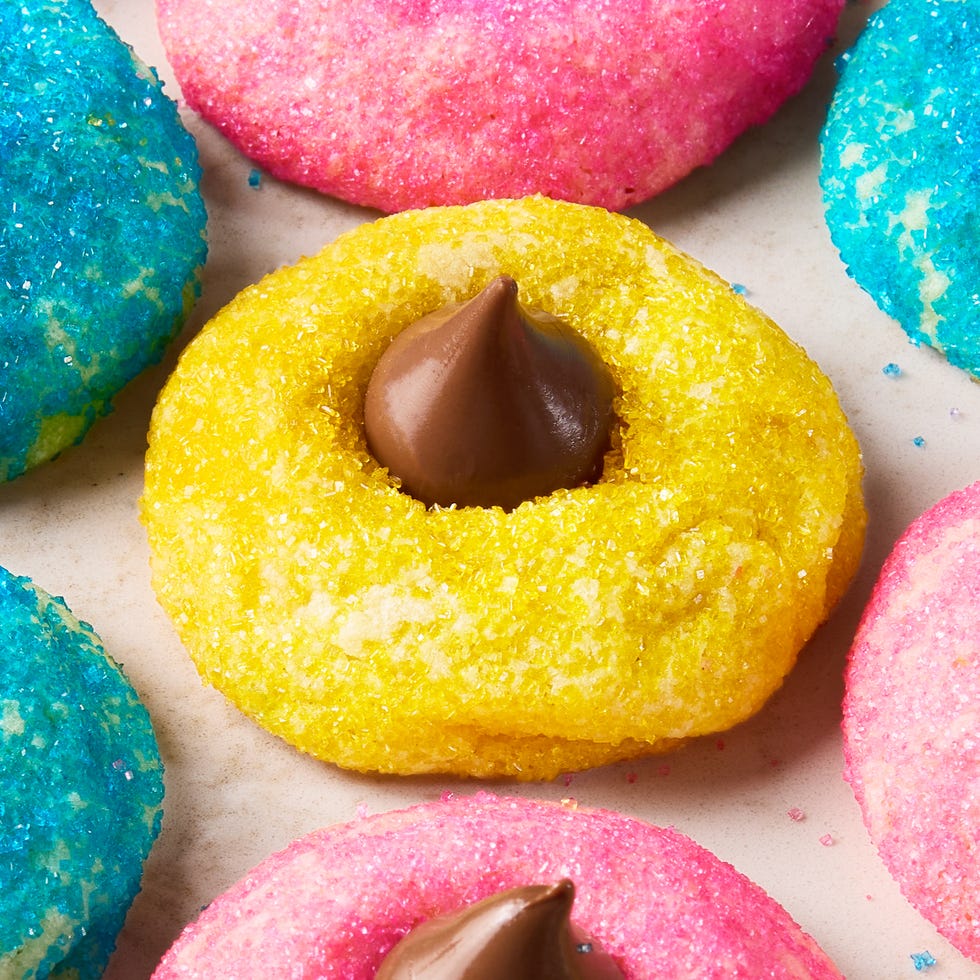 blue pink and yellow dyed cookies with sugar and topped with a hershey kiss