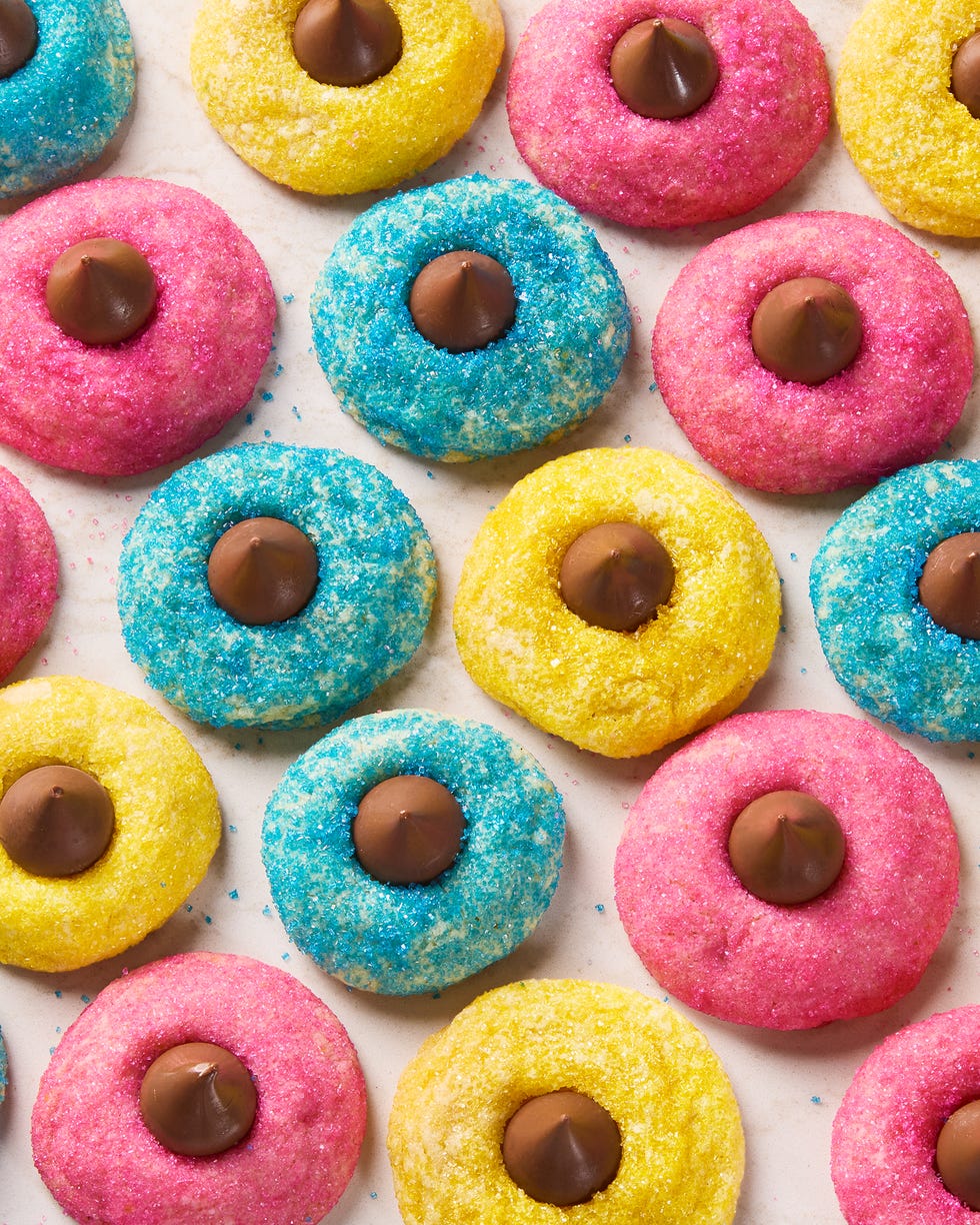blue pink and yellow dyed cookies with sugar and topped with a hershey kiss