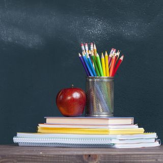 pencil tray and an apple on notebooks on school teacher's desk