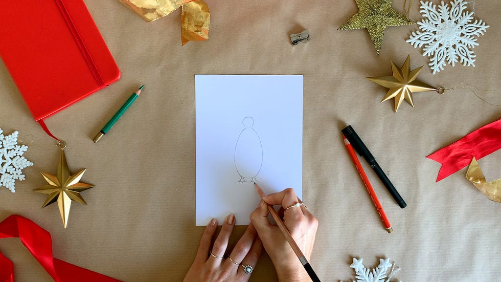 a person drawing penguin feet on a piece of paper