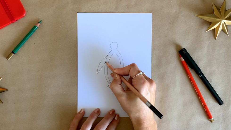 a person drawing a penguin on a piece of paper