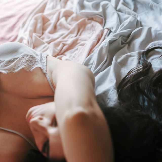 pensive brunette girl with hair forming a heart lying on the bed