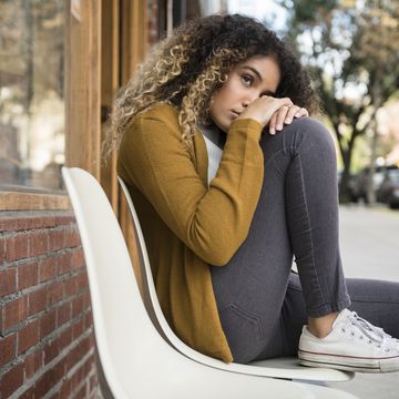 Pensive Mixed Race woman sitting on chair in city