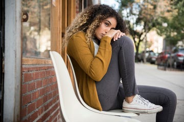 Pensive Mixed Race woman sitting on chair in city