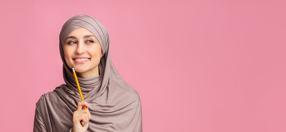 pensive muslim woman in headscarf holding pencil, overthinking about something