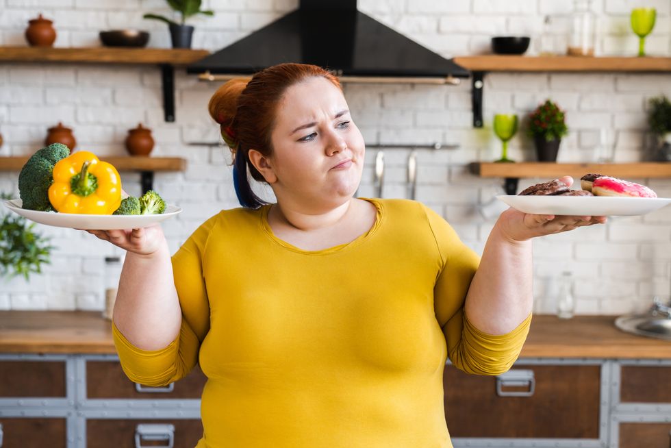 pensive obese caucasian woman opting for junk food and donuts instead of healthy eating dieting concept hard choice between healthy lifestyle and bad eating habits