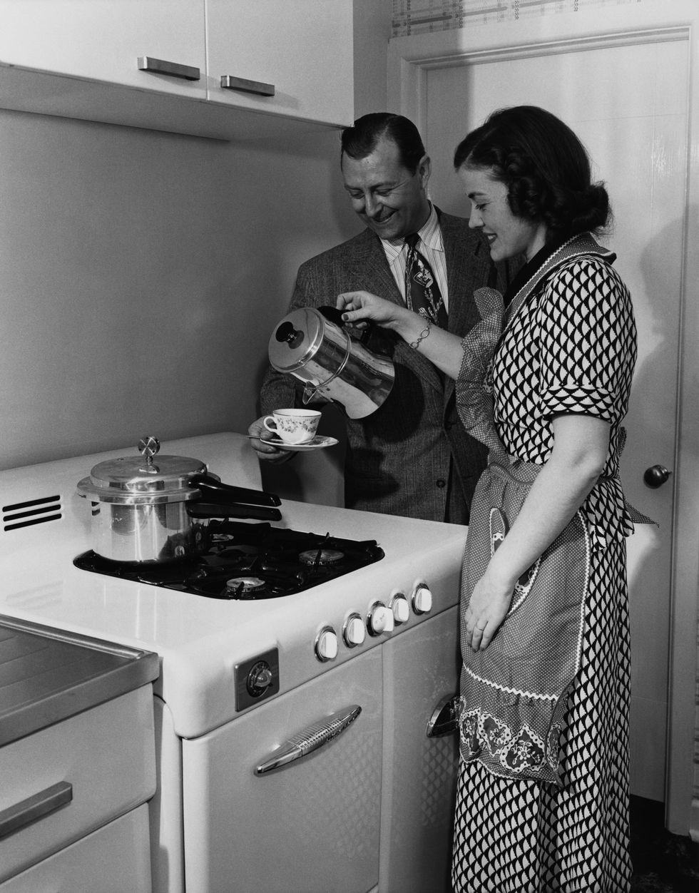 MID ADULT WOMEN POURING COFFEE TO HER HUSBAND