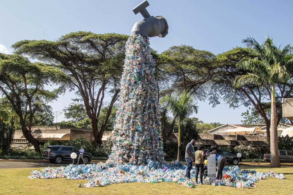 people are seen next to a plastic waste art installation by