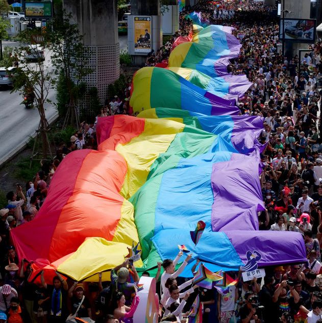 people carry a flag in a parade to kick off bangkok pride