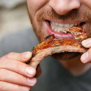 people eat food man eating barbecue ribs in grill bar closeup