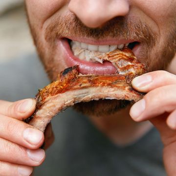 people eat food man eating barbecue ribs in grill bar closeup