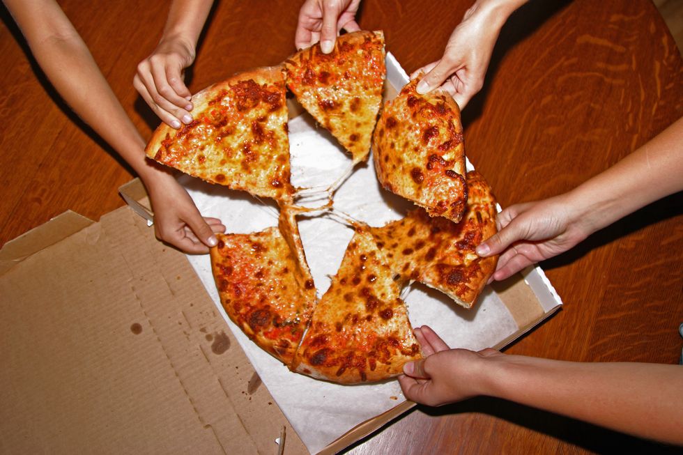 people grabbing slices of pizza, overhead view