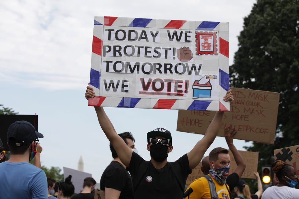 man holding up sign that reads 'today we protest tomorrow we vote'