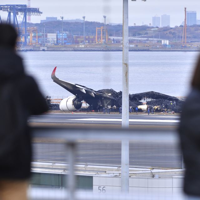 tokyo japan january 03 people look at police and officials inspecting the wreckage of japan airlines aircraft jal flight 516 on the tarmac of tokyo haneda airport on january 3rd 2024 in tokyo japan a day after a collision, during landing with an aircraft operated by the japan coast guard