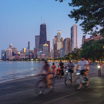 people riding bicycles at night with chicago skyline in background