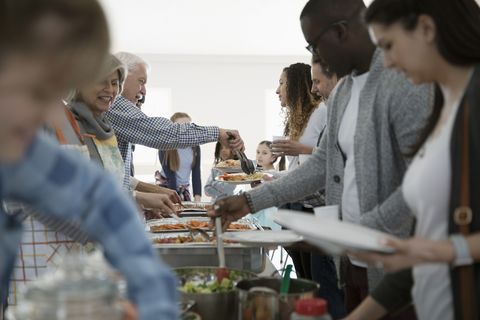thanksgiving traditions   people serving food at a soup kitchen over a line of aluminum warming trays