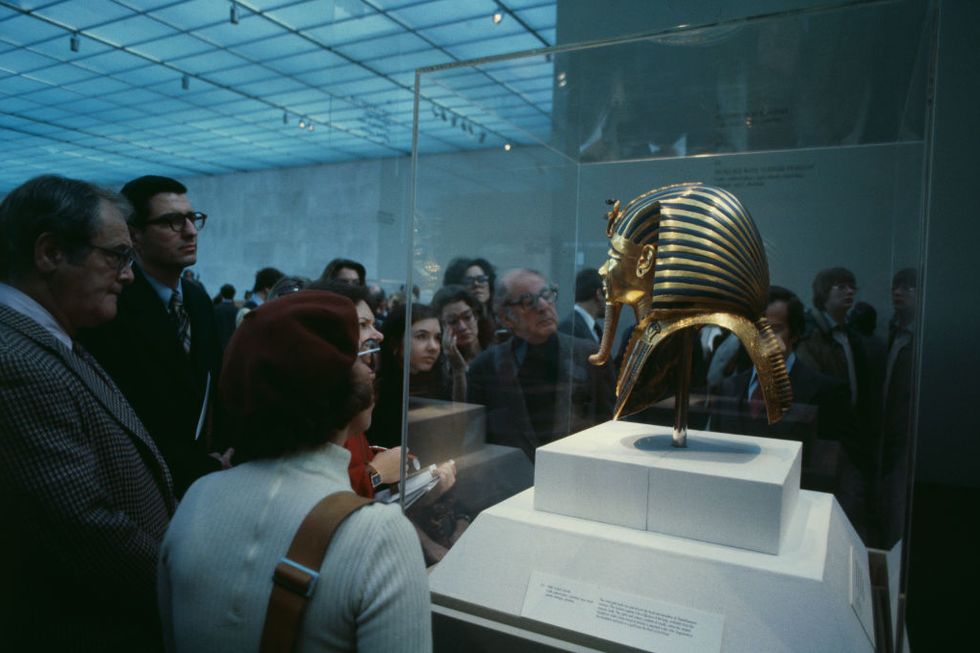 people looking at a gold funerary mask exhibit at a museum