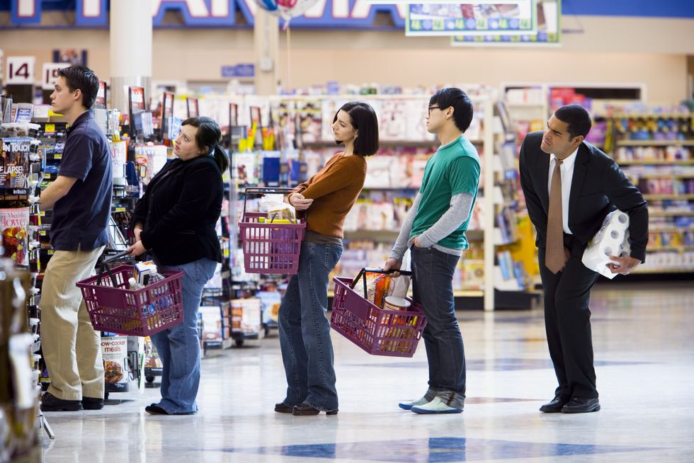 people waiting in line with shopping baskets at grocery store