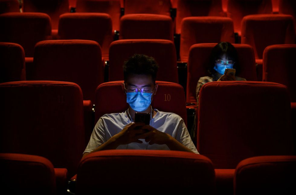 hombre consultando el móvil en un cine de pekín