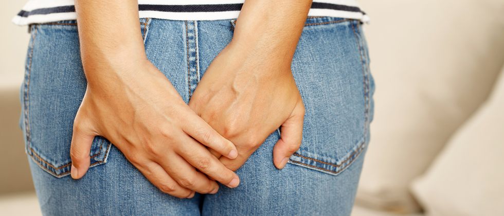 people woman hand holding her bottom because having abdominal anal pain and suffering from hemorrhoids