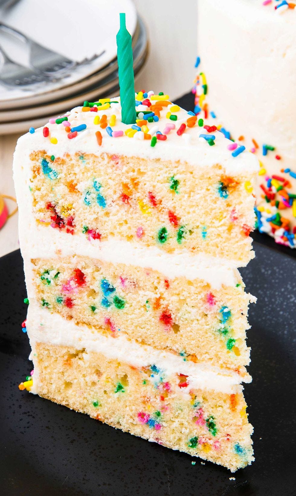slice of cake studded with sprinkles and layered with white buttercream
