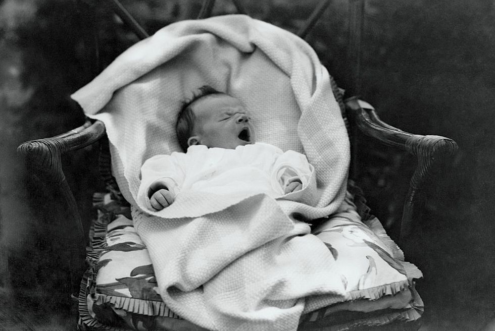 charles lindbergh jr yawns while swattled in a blanket as he lies on a chair
